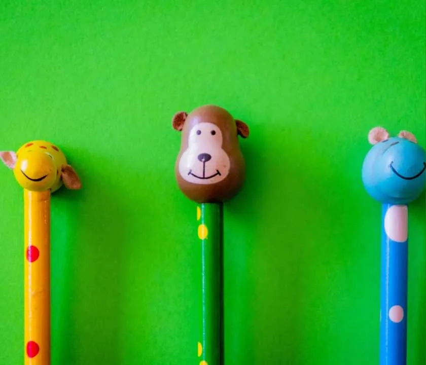Three differently coloured pencils with different pencil toppers