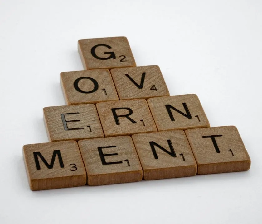 Scrabble tiles laid out in a pyramid shape spelling the word 'government'.
